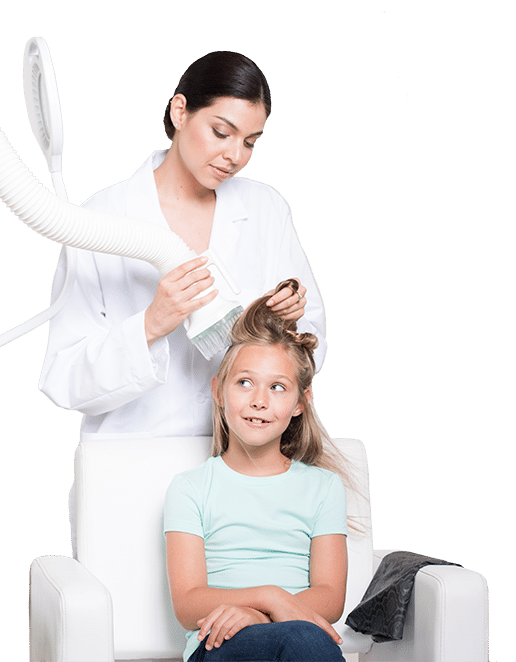 Technician performing heated air head lice treatment on blond child