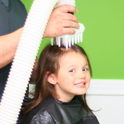 Little girl with brown hair smiling at the camera with the AirAllé device right on the top of her head